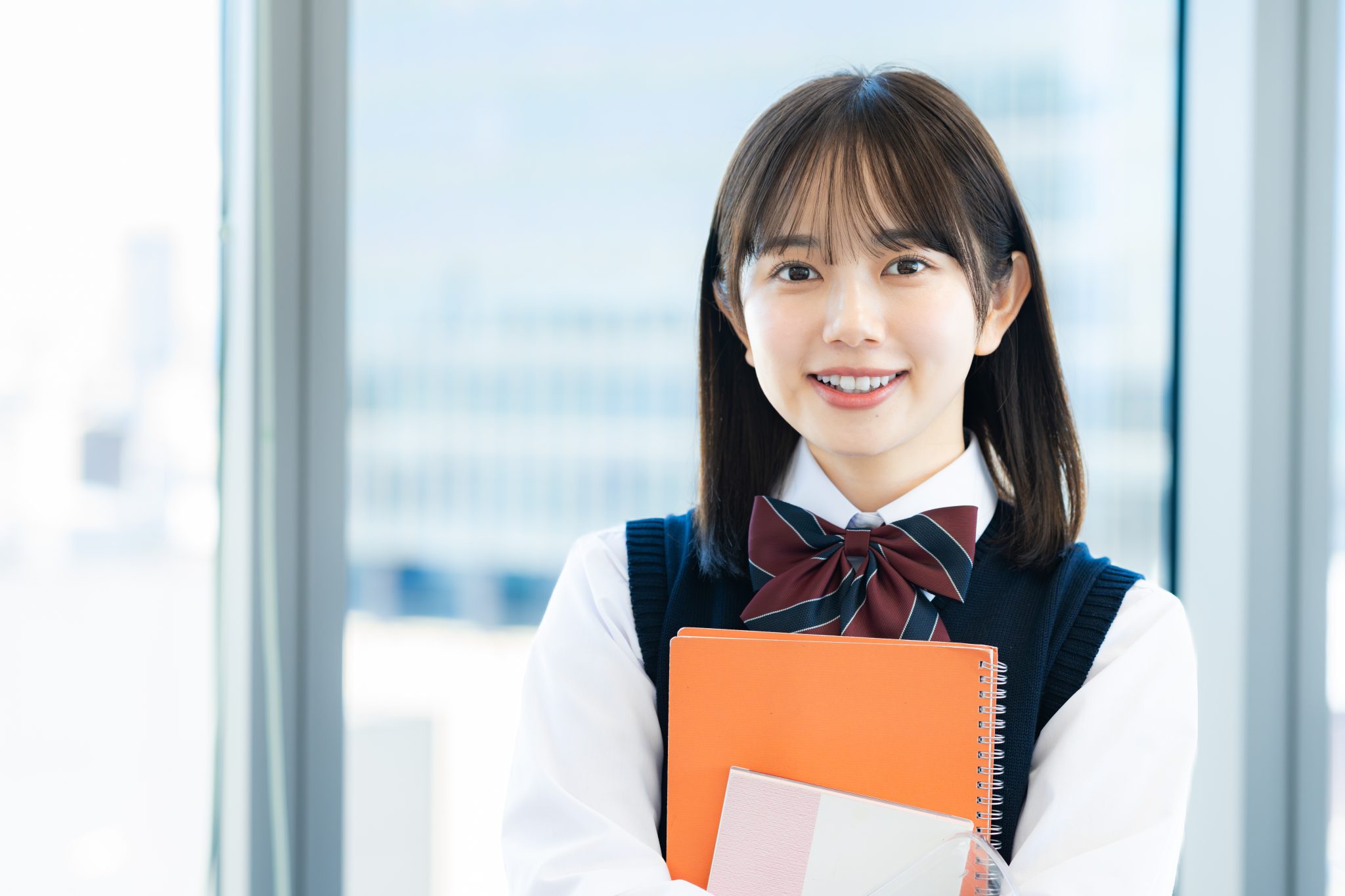 ノートを持って微笑む制服姿の学生