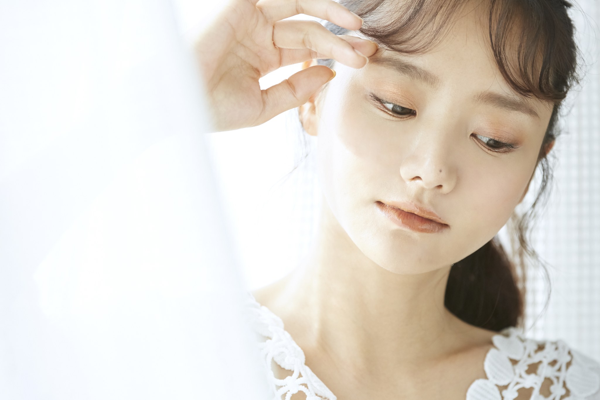 明るい光の中で頬に手を添える女性